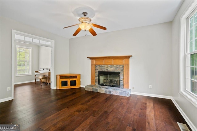 unfurnished living room with hardwood / wood-style floors, ceiling fan, baseboards, and a tiled fireplace