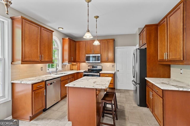 kitchen with stainless steel appliances, a sink, a center island, and brown cabinetry