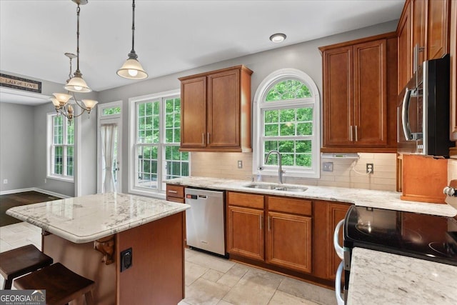 kitchen featuring appliances with stainless steel finishes, a sink, plenty of natural light, and a center island