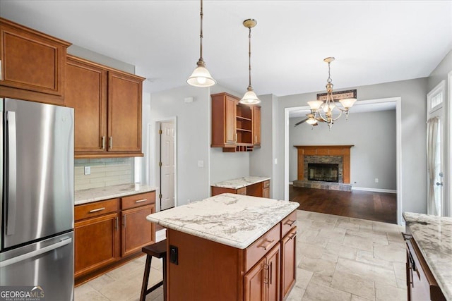 kitchen with freestanding refrigerator, backsplash, a chandelier, and brown cabinets