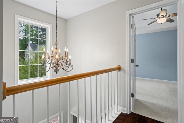 hallway with a chandelier and baseboards