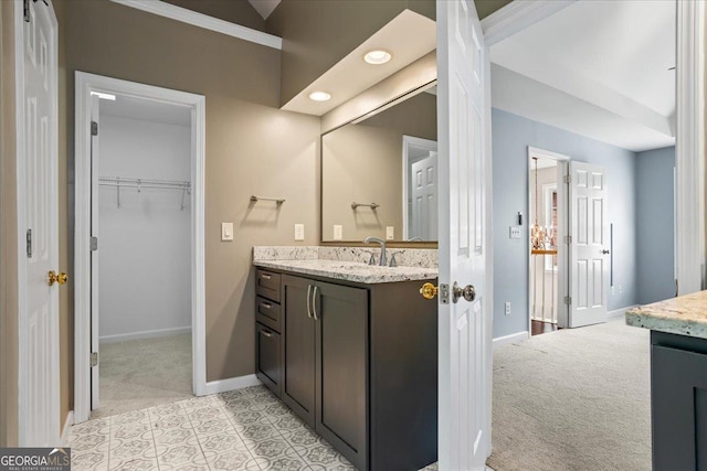 bathroom with baseboards, vanity, recessed lighting, and a spacious closet
