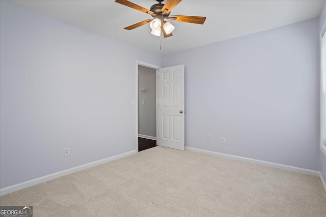 carpeted empty room featuring a ceiling fan and baseboards
