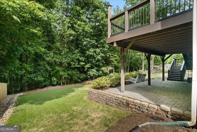 view of grassy yard featuring stairway, a patio, and a wooden deck