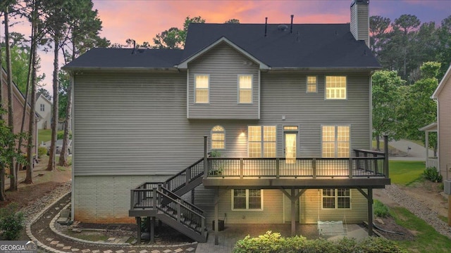 rear view of house featuring a wooden deck, stairs, a chimney, and a patio