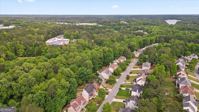 aerial view of property's location featuring a forest and nearby suburban area