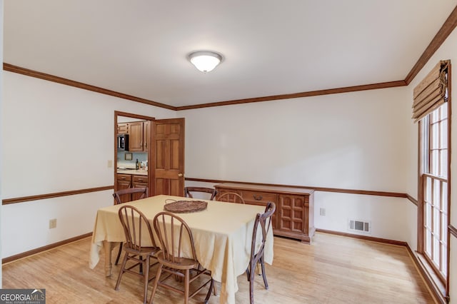 3741 Windhurst Dr SW, Lilburn, GA 30047 - dining room with light wood-style floors, ornamental molding, and baseboards
