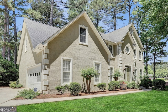 view of front of home featuring stucco siding, a garage, driveway, and a front yard