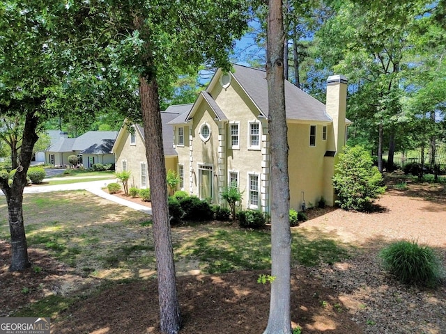 view of front of home with a chimney and stucco siding