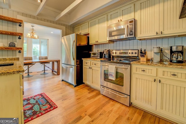 22 Waters Bridge Cir, Covington, GA 30014 - kitchen with appliances with stainless steel finishes, light wood-style floors, beam ceiling, cream cabinetry, and light stone countertops