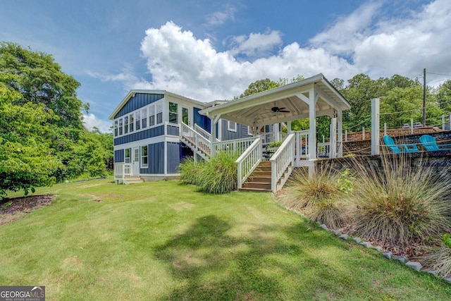 22 Waters Bridge Cir, Covington, GA 30014 - rear view of house with a ceiling fan, a yard, stairway, board and batten siding, and covered porch