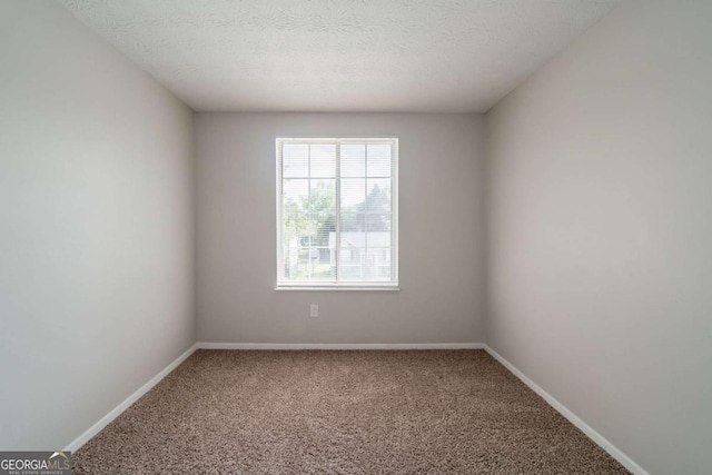 spare room featuring carpet, baseboards, and a textured ceiling