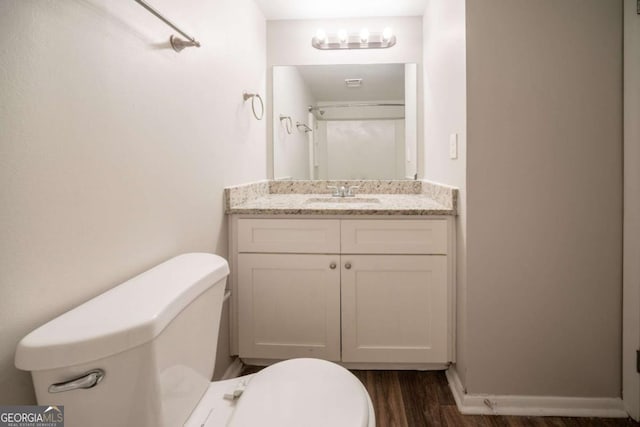 bathroom with toilet, wood finished floors, vanity, and baseboards