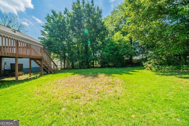 view of grassy yard featuring stairs and a wooden deck