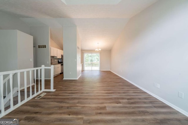 unfurnished room featuring a chandelier, dark wood-type flooring, baseboards, and lofted ceiling