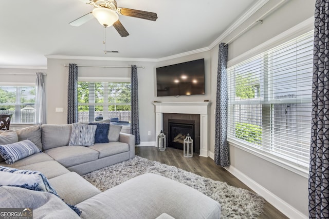 living room with ceiling fan, crown molding, baseboards, a tile fireplace, and wood finished floors