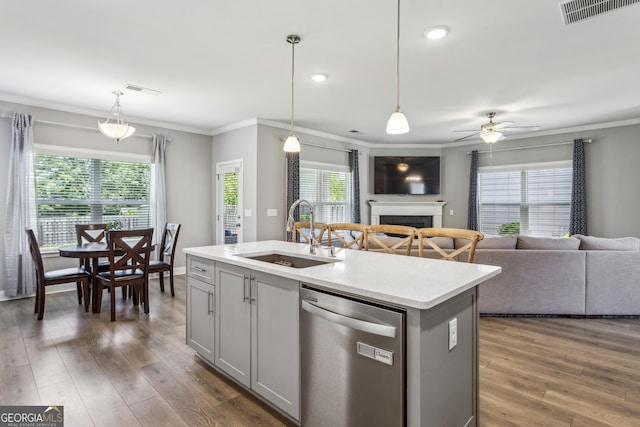 kitchen featuring stainless steel dishwasher, a sink, gray cabinetry, a fireplace, and open floor plan
