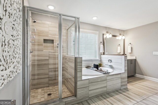 bathroom with a stall shower, a bath, and vanity