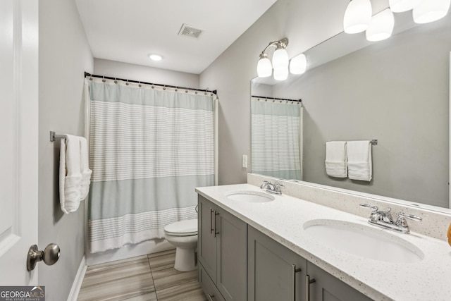 bathroom featuring toilet and double vanity