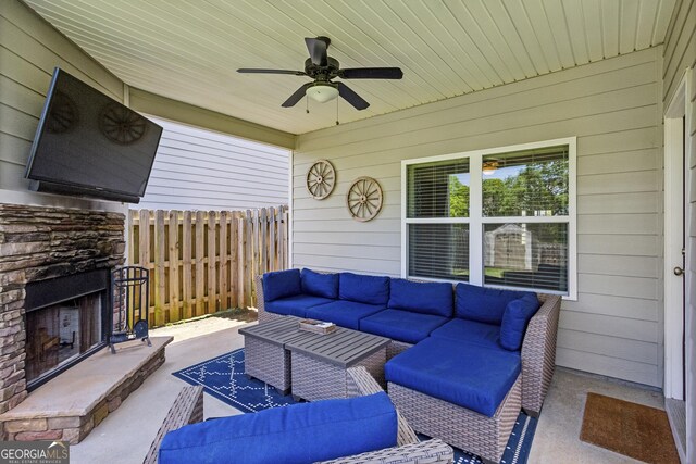 view of patio / terrace with an outdoor living space with a fireplace, fence, and a ceiling fan