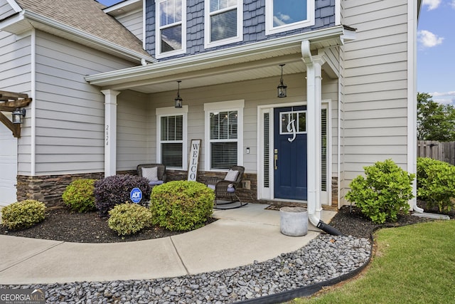 property entrance with covered porch, a shingled roof, and stone siding