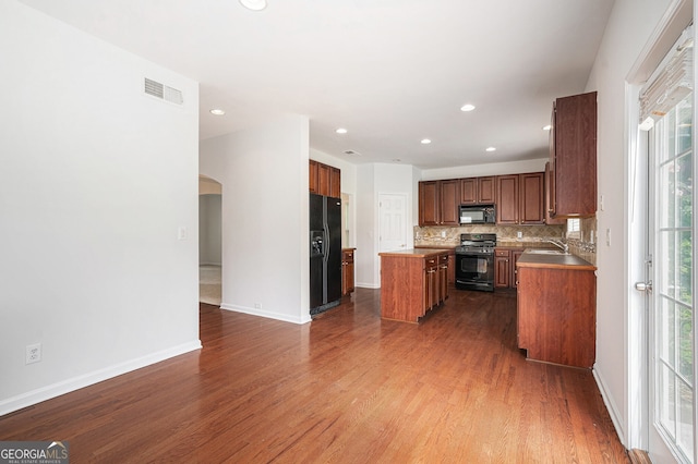 7280 Wright Dr, Atlanta, GA 30349 - kitchen featuring black appliances, arched walkways, a kitchen island, tasteful backsplash, and dark wood-style flooring