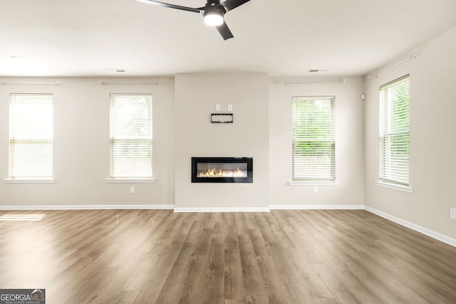 116 Cabin Way, Hampton, GA 30228 - unfurnished living room with wood finished floors, a glass covered fireplace, baseboards, and a ceiling fan