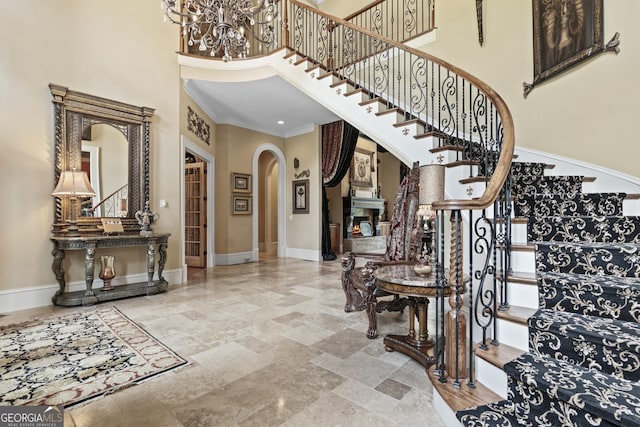 foyer with arched walkways, a high ceiling, stairway, baseboards, and stone tile flooring