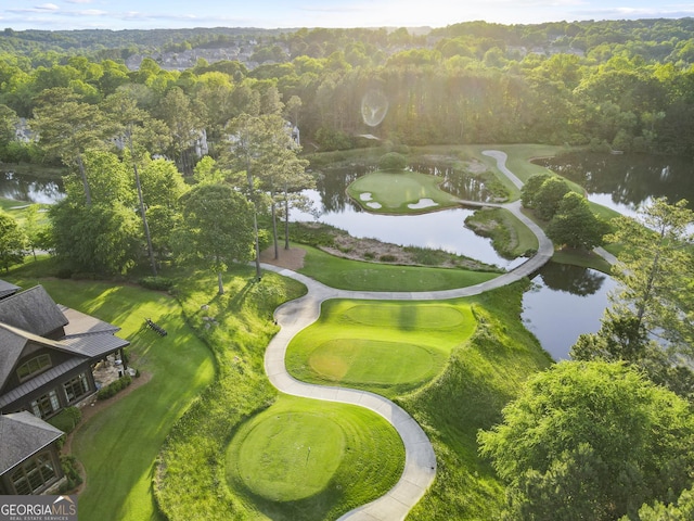 drone / aerial view of a nearby body of water, a heavily wooded area, and a local golf course