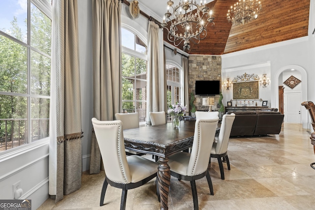 dining area featuring a chandelier, high vaulted ceiling, healthy amount of natural light, arched walkways, and ornamental molding