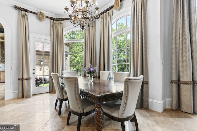 dining room with a chandelier, crown molding, arched walkways, stone tile flooring, and baseboards