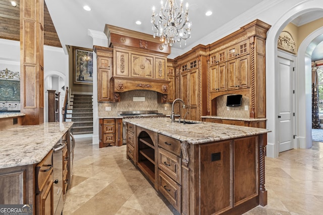 kitchen featuring arched walkways, a sink, ornamental molding, a center island with sink, and decorative backsplash