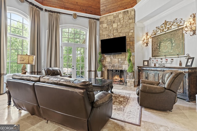 living area with a stone fireplace, a towering ceiling, and ornamental molding