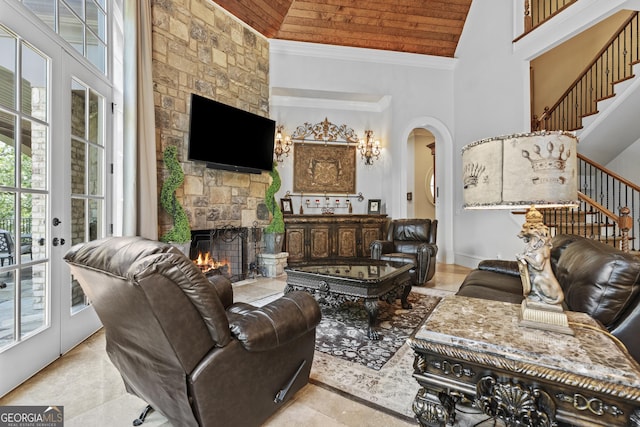 living area featuring high vaulted ceiling, wooden ceiling, a stone fireplace, stairs, and arched walkways