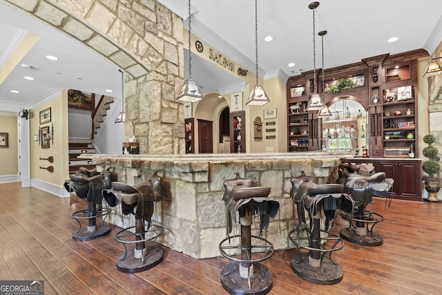 community bar area featuring crown molding, wood-type flooring, arched walkways, stairs, and recessed lighting
