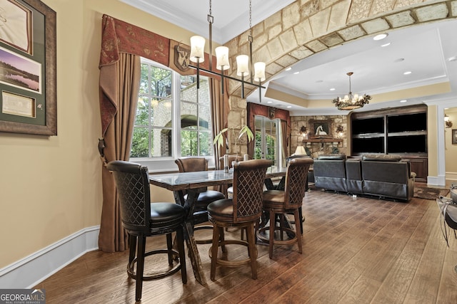 dining room with a chandelier, crown molding, dark wood-style flooring, plenty of natural light, and a raised ceiling