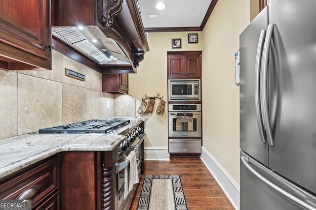kitchen with appliances with stainless steel finishes, a warming drawer, tasteful backsplash, ornamental molding, and premium range hood