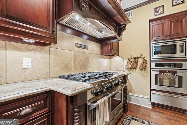 kitchen with appliances with stainless steel finishes, premium range hood, a warming drawer, decorative backsplash, and baseboards
