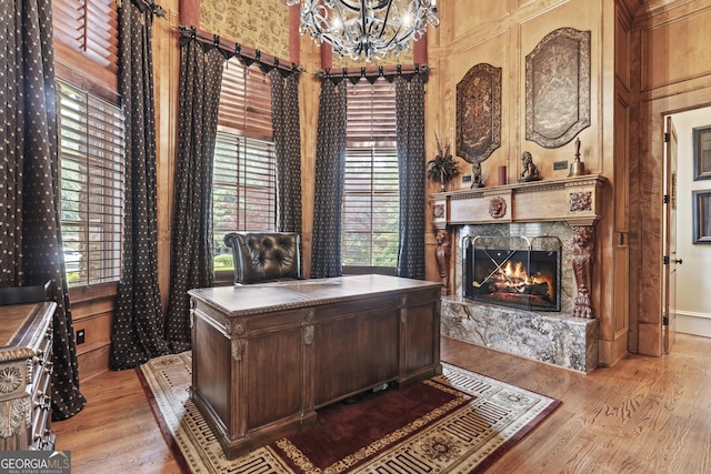 office space with a chandelier, a high ceiling, a premium fireplace, wood finished floors, and healthy amount of natural light