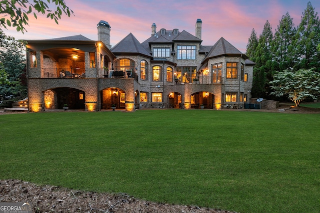 back of property featuring a balcony, a yard, and a chimney