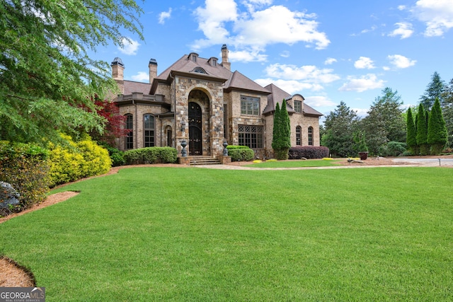 view of front facade featuring stone siding, a front lawn, and a chimney