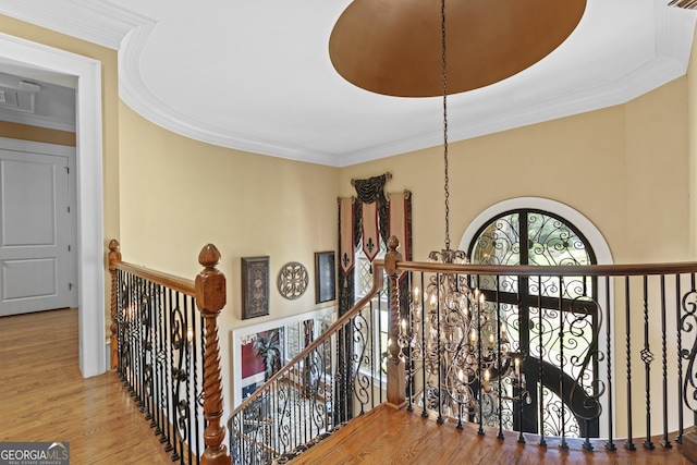 hall featuring an upstairs landing, crown molding, wood finished floors, and a chandelier