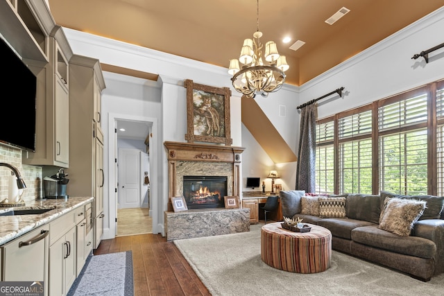 living area with a chandelier, a premium fireplace, a high ceiling, dark wood-style flooring, and recessed lighting