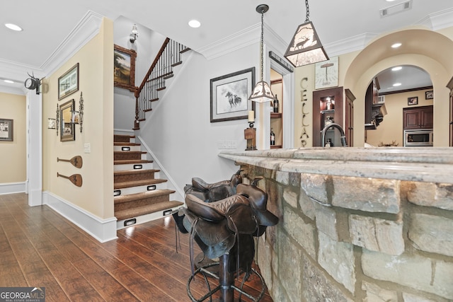 bar with stainless steel microwave, recessed lighting, crown molding, wood finished floors, and stairway