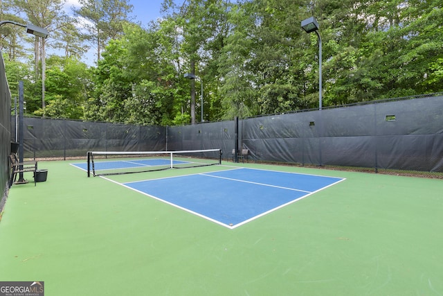 view of tennis court featuring community basketball court and fence