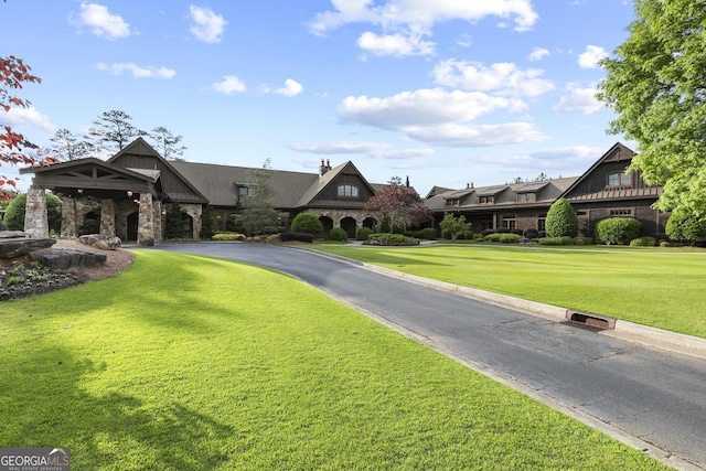 view of front of property featuring stone siding, a front yard, and a chimney