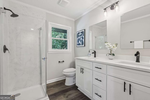 bathroom featuring toilet, a stall shower, crown molding, wood finished floors, and double vanity