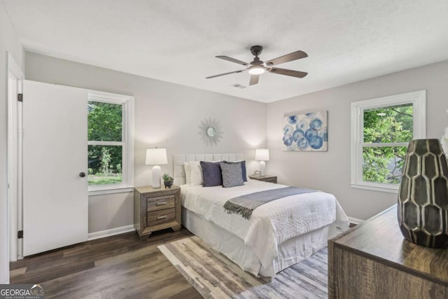 bedroom featuring multiple windows, dark wood-style flooring, baseboards, and ceiling fan