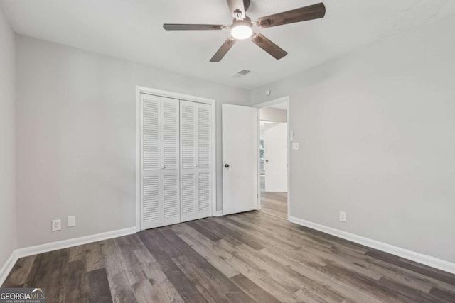 unfurnished bedroom with wood finished floors, baseboards, a closet, and ceiling fan