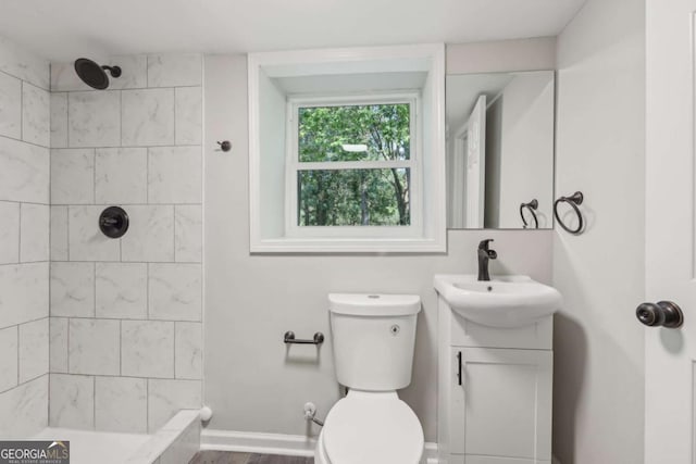 full bathroom featuring a tile shower, toilet, and vanity